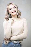 un' bellissimo giovane ragazza con biondo capelli e blu occhi sembra a il telecamera e sorrisi. foto