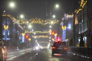sfocato sera città con macchine e luci di multicolore lanterne. foto