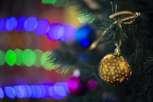 d'oro Natale palla su il Natale albero contro il sfondo di multicolore bokeh. foto