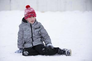 il ragazzo si siede nel il neve nel inverno. foto