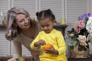 multietnico mamma e figlia giocare a casa nel il cucina. allegro madre con poco figlia di africano nazionalità. famiglia a partire dal diverso gare. foto