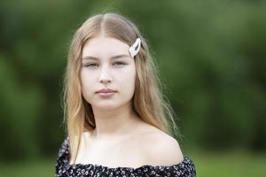 ritratto di un' bellissimo ragazza con lungo capelli su un' estate sfondo. il viso di un' biondo adolescenziale ragazza. foto