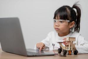 gli studenti asiatici imparano a casa a codificare auto robot e cavi di schede elettroniche in stelo, vapore, matematica ingegneria scienza tecnologia codice informatico in robotica per bambini concetto. foto