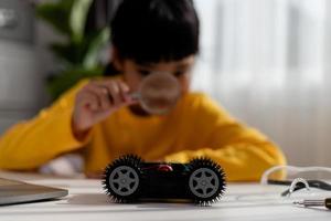 gli studenti asiatici imparano a casa a codificare auto robot e cavi di schede elettroniche in stelo, vapore, matematica ingegneria scienza tecnologia codice informatico in robotica per bambini concetto. foto