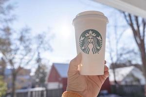 marinette,wi,usa - nov14, 2023- tazze di Starbucks caldo caffè mettere su bianca neve nel inverno giardino, fresco e caldo bevanda prendere lontano concept.starbucks bar caffè negozio. foto