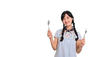 ritratto di bellissimo giovane asiatico donna Sorridi nel denim vestito con cucchiaio e forchetta su bianca sfondo foto