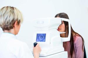 femmina medico oculista è controllo il occhio visione di attraente giovane donna nel moderno clinica. medico e paziente nel oftalmologia clinica. foto