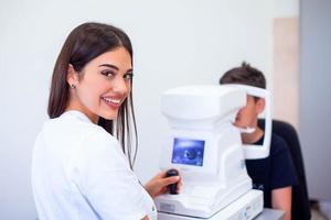 femmina oculista utilizzando macchina per controllo occhio vista nel clinica. poco ragazzo guardare a attrezzatura e medico analisi occhio allievo nel ottico negozio. concetto di occhio cura e Salute. foto