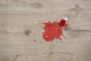 bicchiere di rosso vino abbattere su laminato, vino rovesciato su pavimento. foto