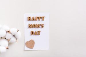 contento La madre di giorno. un' foglio di carta con lettere e un' ramo di cotone su un' leggero sfondo. foto