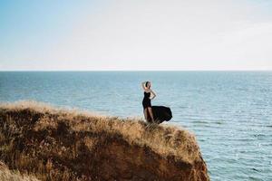 alto ragazza modello nel un' nero vestito su il montagna colline foto