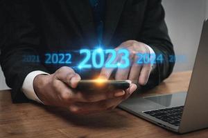 tendenza di 2023. persone attività commerciale investitore utilizzando mobile Telefono con virtuale 2023 anno diagramma, attività commerciale tendenza, modificare a partire dal 2022 per 2023, strategia, investimento, attività commerciale pianificazione e contento nuovo anno concetto foto