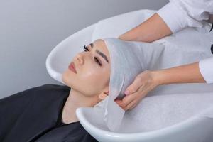 professionale parrucchiere lavaggio capelli di giovane donna nel bellezza salone. vicino su di donna di capelli nel bellezza salone, acconciatura concetto foto