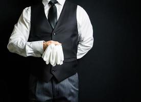 ritratto di maggiordomo nel buio completo da uomo Tenere pulito bianca guanti. copia spazio per servizio industria e professionale cortesia. foto