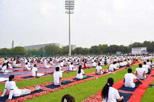 nuovo delhi, India, giugno 21 2022 - gruppo yoga esercizio sessione per persone a yamuna gli sport complesso nel delhi su internazionale yoga giorno, grande gruppo di adulti frequentando yoga classe nel cricket stadio foto