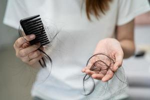 la donna asiatica ha problemi con la caduta dei capelli lunghi attaccata alla spazzola del pettine. foto