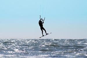 silhouette di aquilone surfer nel un' mare foto