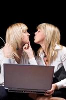 Due baci donne d'affari con il computer portatile. isolato su nero foto
