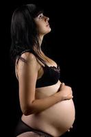 incinta giovane brunetta nel biancheria intima. isolato foto