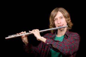il giovane uomo giochi un' flauto al di sopra di nero foto