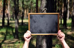 umano mani Tenere un vuoto di legno telaio con un' nero sfondo foto