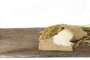biologico bianca riso o gelsomino riso nel un' sacco posto su un' di legno pavimento su un' bianca sfondo foto