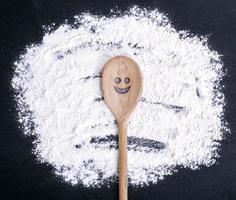 cucchiaio con un' lavorato sorridente viso bugie su sparpagliato Farina foto