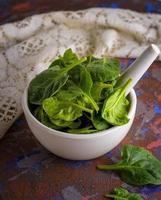 fresco verde spinaci le foglie nel un' bianca ceramica mortaio foto