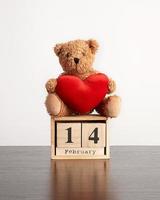 di legno calendario di cubi con il Data di febbraio 14 e un' Marrone orsacchiotto orso su un' nero tavolo foto