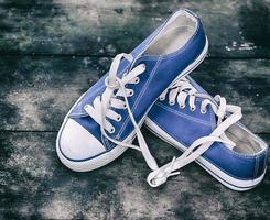 paio di logoro blu scarpe da ginnastica gioventù su un vecchio di legno superficie foto