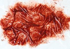 rovesciato rosso vernice con scintille sotto trasparente polietilene su un' bianca sfondo foto