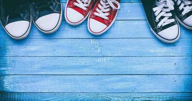 tre coppie di indossare scarpe da ginnastica su un' blu di legno superficie, superiore Visualizza foto