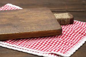 vecchio di legno taglio tavola e piegato rosso e bianca cotone cucina tovagliolo su un' di legno Marrone sfondo, superiore Visualizza foto