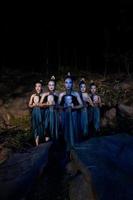 un' gruppo di giavanese donne in piedi nel il boschi fra il rocce mentre Tenere un' di legno maschera foto