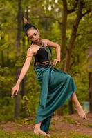 indonesiano donna danza nel il foresta mentre indossare un' tradizionale verde costume durante il Festival foto