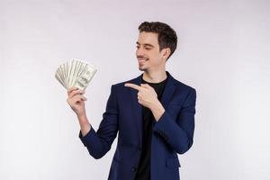 ritratto di un' allegro uomo puntamento dito a mazzo di i soldi banconote al di sopra di bianca sfondo foto
