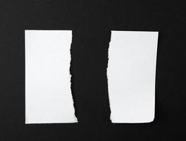 strappato nel metà vuoto bianca foglio di carta su nero sfondo foto
