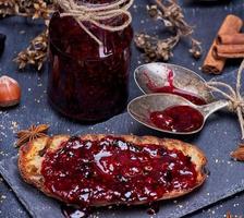 crostini con lampone marmellata e vuoto marmellata vaso con un ferro cucchiaio foto