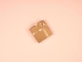 chiuso d'oro regalo scatola con un' arco su un' beige sfondo foto