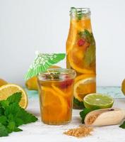 estate rinfrescante bevanda limonata con limoni, mirtillo, menta foglie, lime nel un' bicchiere bottiglia foto