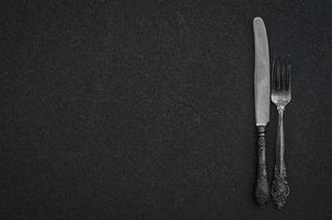argento forchetta e coltello su il nero superficie foto