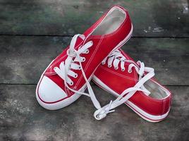 paio di rosso scarpe da ginnastica gioventù su un vecchio di legno superficie foto