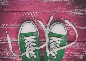 paio di logoro scarpe da ginnastica su un' rosa verde vecchio di legno superficie foto