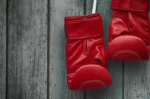 paio di rosso boxe guanti su un vecchio squallido di legno parete foto