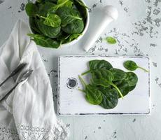 verde spinaci le foglie su un' bianca di legno tavola foto