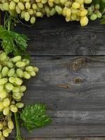 grappoli di uva telaio su grigio di legno sfondo foto