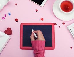 giusto femmina mano nel un' rosa maglione con un' pezzo di bianca gesso foto