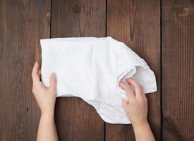 mani hold bianca cucina asciugamano su un' Marrone di legno sfondo foto