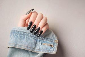 mano di un' giovane ragazza con nero manicure su Chiodi foto