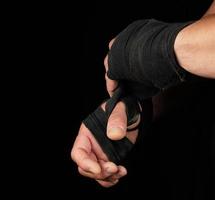 uomo impacchi il suo mani nel nero tessile bendare per gli sport foto
